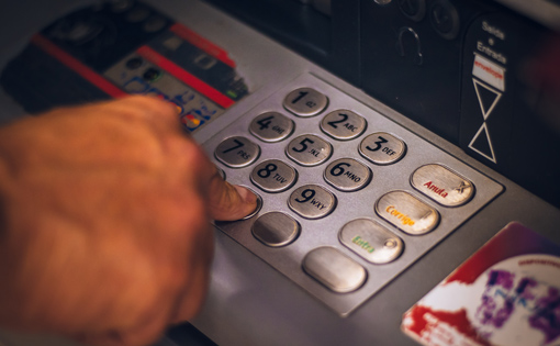 Someone entering their PIN into an ATM.